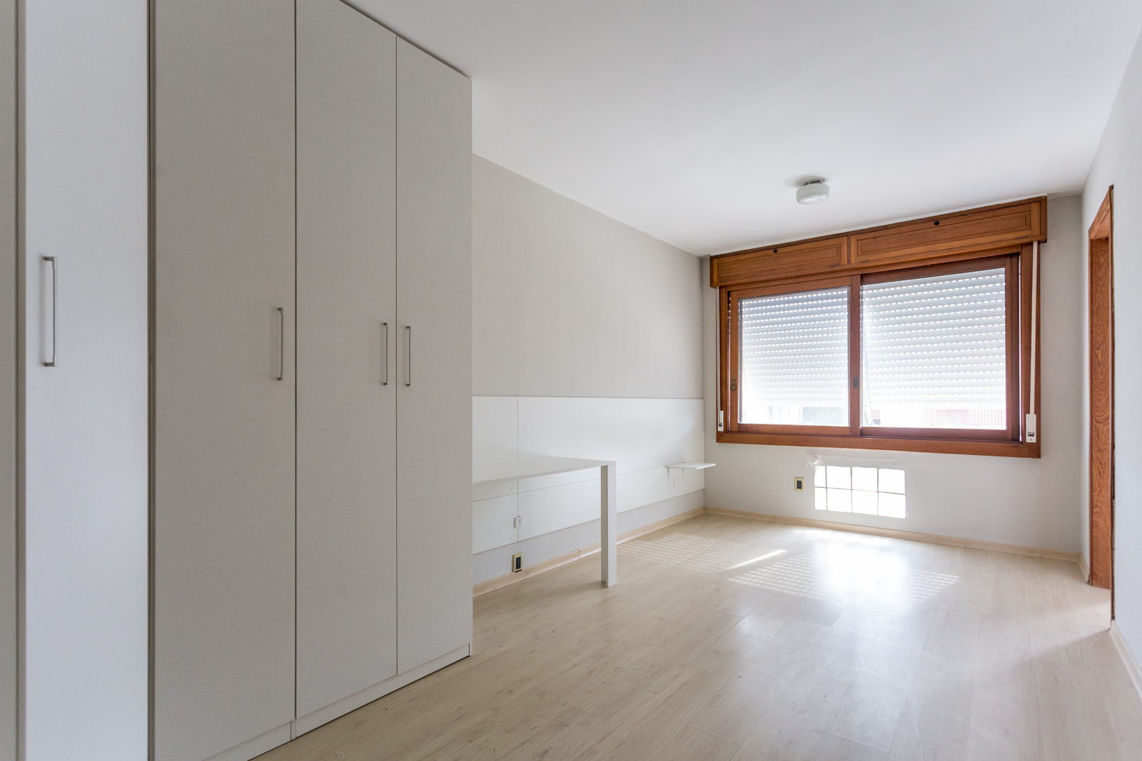Sala com armários embutidos brancos e janela de madeira